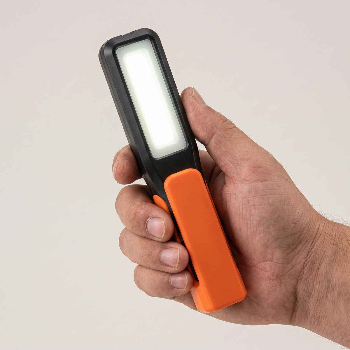Pivot work light held in hand to show its slim size