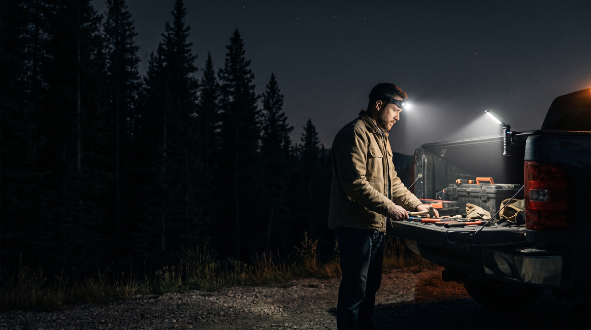 Man working at a pickup tailgate at night lit by a Warden headlamp and work light